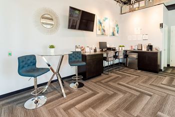 a communal area with a table and chairs and a kitchen with a sink